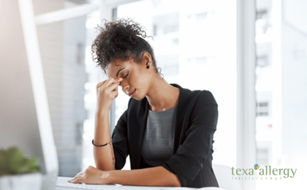 woman showing headache or sinus symptoms, with the Texa allergy Logo in the bottom right corner.